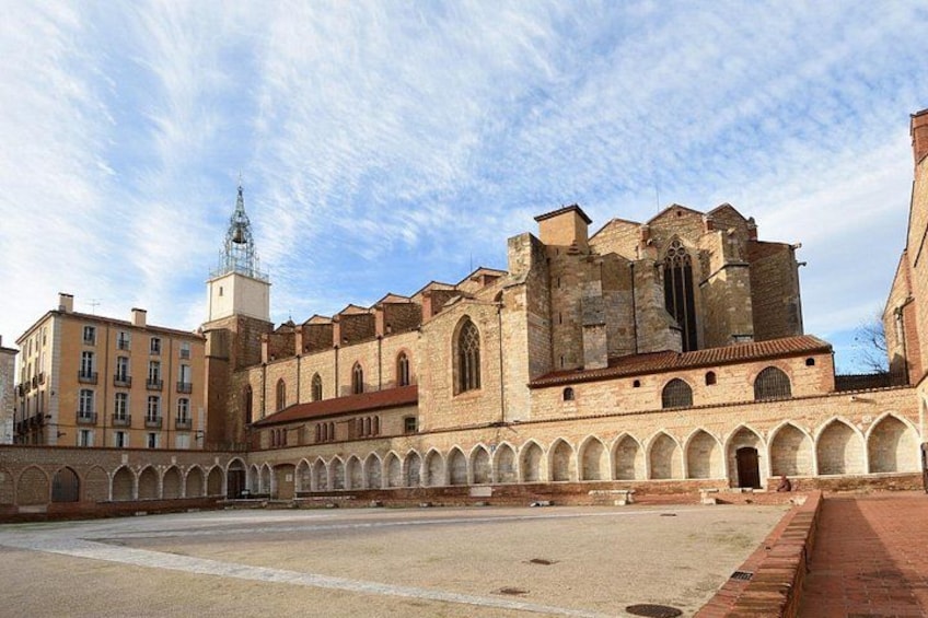 A historic building with a courtyard, arched walkways, and a tower. 1