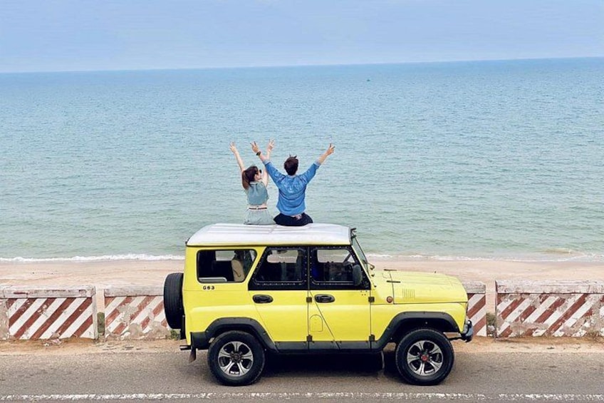 Un SUV giallo parcheggiato sulla spiaggia, con una persona che alza le braccia. 4