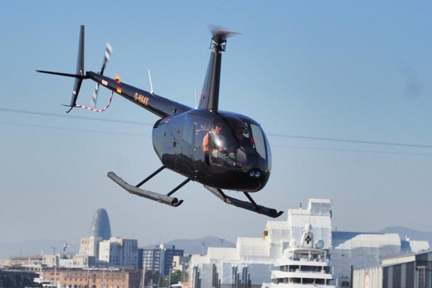 A helicopter with the registration number 0-441K flying over a cityscape with buildings and a dome-shaped structure in the background. 2