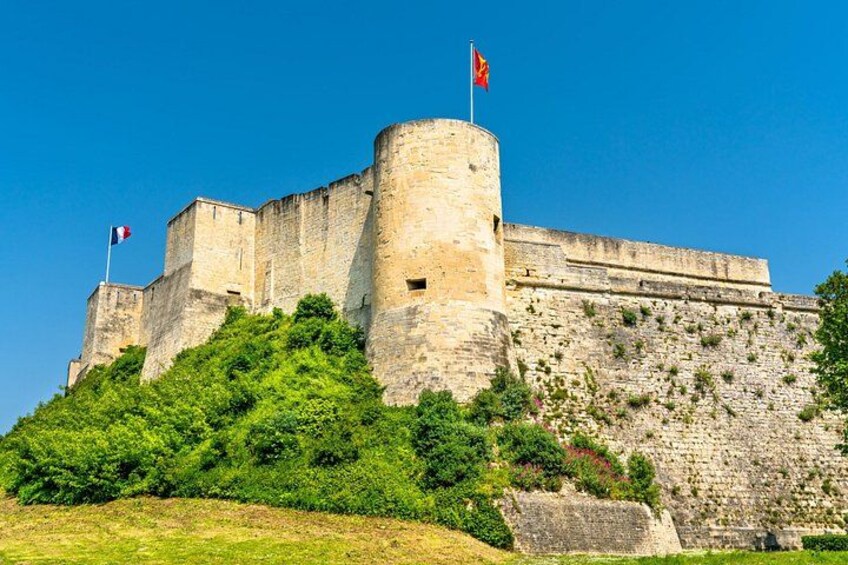 A historic stone castle with a flag, surrounded by lush greenery. 1