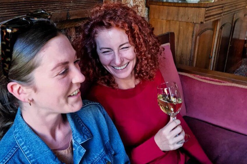 Deux personnes sont assises sur un canapé, l’une d’elles tenant un verre de vin. 1