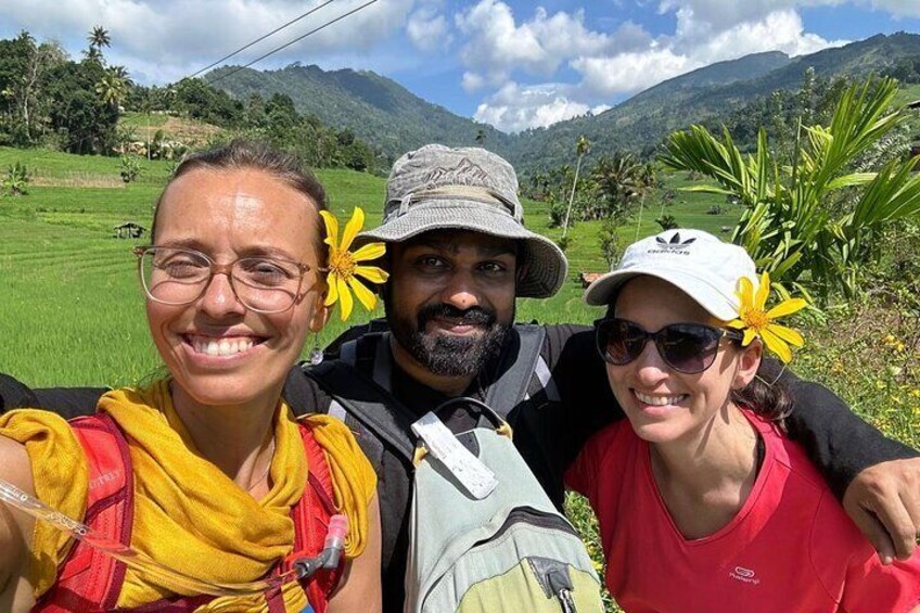 Three people in a natural landscape with green fields and mountains in the background. 2