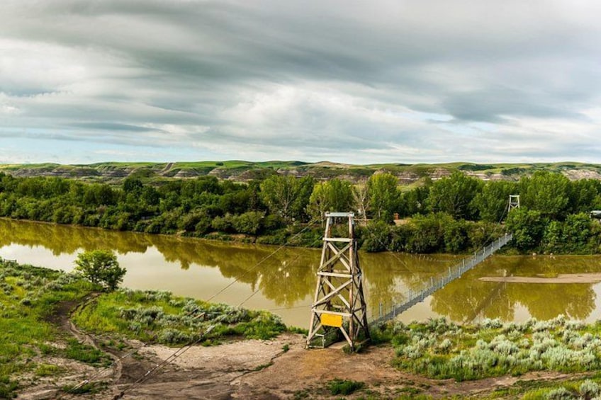 A suspension bridge over a river, surrounded by greenery and hills. 1