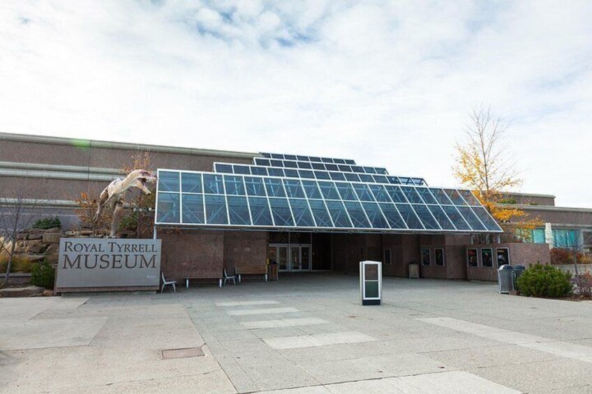 The Royal Tyrrell Museum with a glass roof and a large dinosaur sculpture in front. 4
