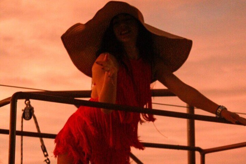 A person wearing a large hat and a red dress standing on a metal structure. 5