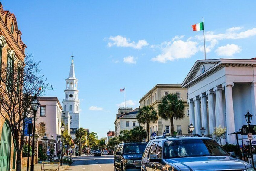 A street with historic buildings, a church tower, and a flag. 2