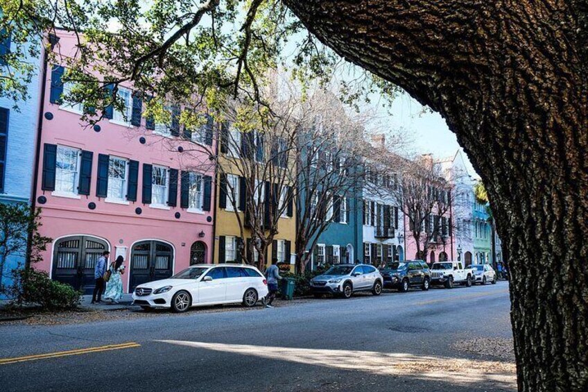 Una calle arbolada con edificios de colores y automóviles estacionados. 3