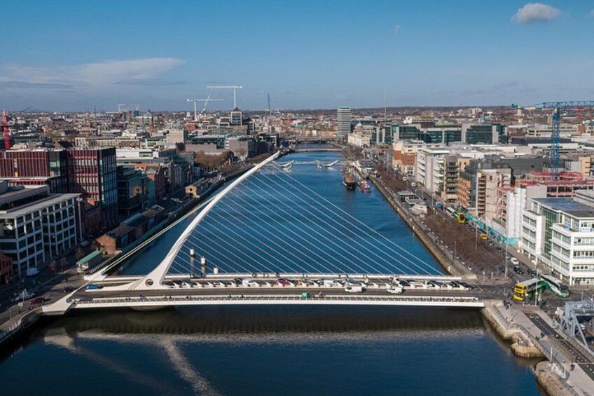 A river with a modern bridge, urban buildings, and a clear sky. 1