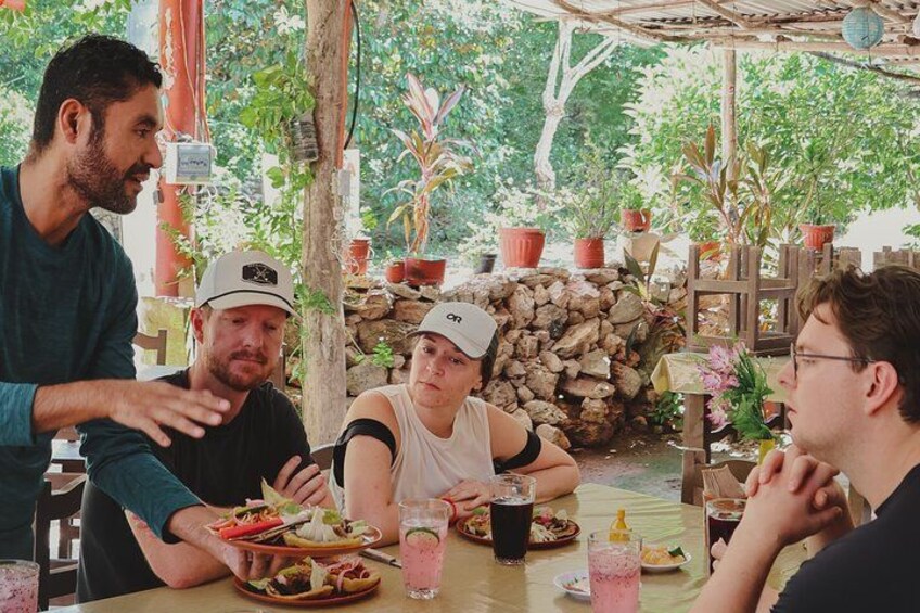 A group of people dining outdoors with a stone wall and potted plants in the background. 2