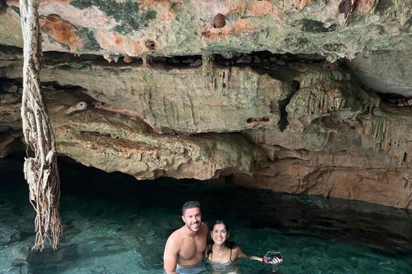 A couple in a cave with clear water and a tree trunk. 3
