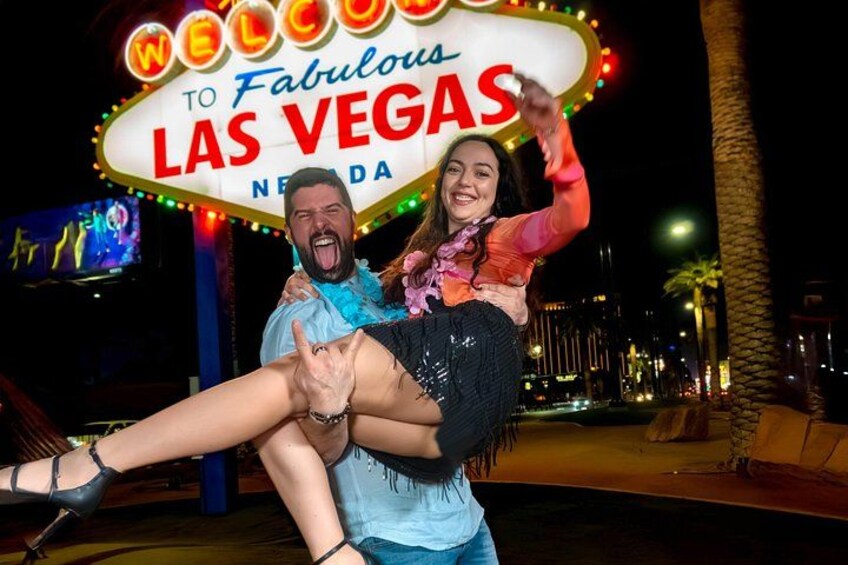 En neonskylt med texten ”VÄLKOMMEN TILL det fantastiska LAS VEGAS” och en person som bär en annan person. 2