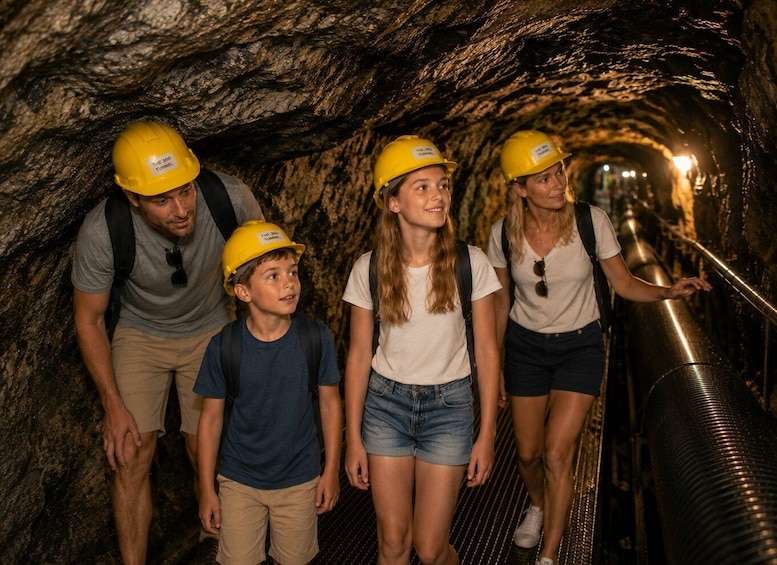 A group of people in a tunnel with rocky walls and a ventilation system. 3