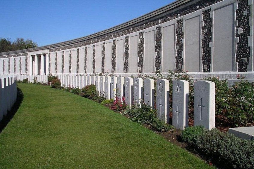 A row of white headstones with crosses, surrounded by well-maintained grass and shrubs. 2