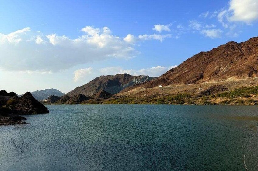 A lake surrounded by mountains, clear water, and a partly cloudy sky. 3