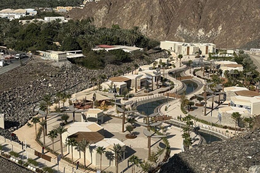 A coastal resort with a pool, palm trees, and a rocky landscape. 4