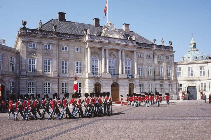 A historic building with a symmetrical facade, a large central entrance, and a flagpole with a flag. 4
