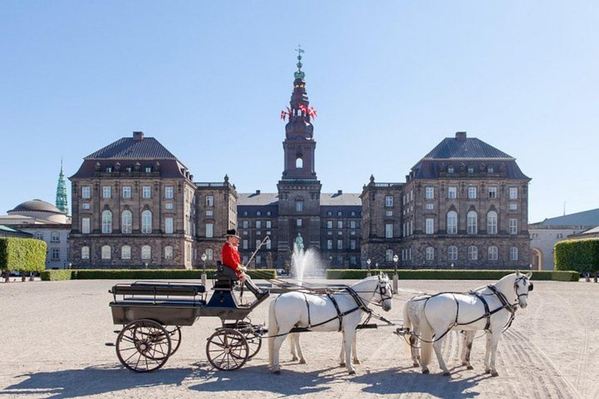 A horse-drawn carriage in front of a large historic building with a clock tower. 2