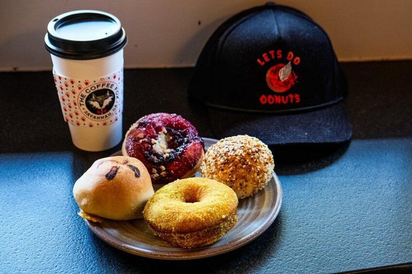 A plate with four donuts, a coffee cup, and a cap. 3