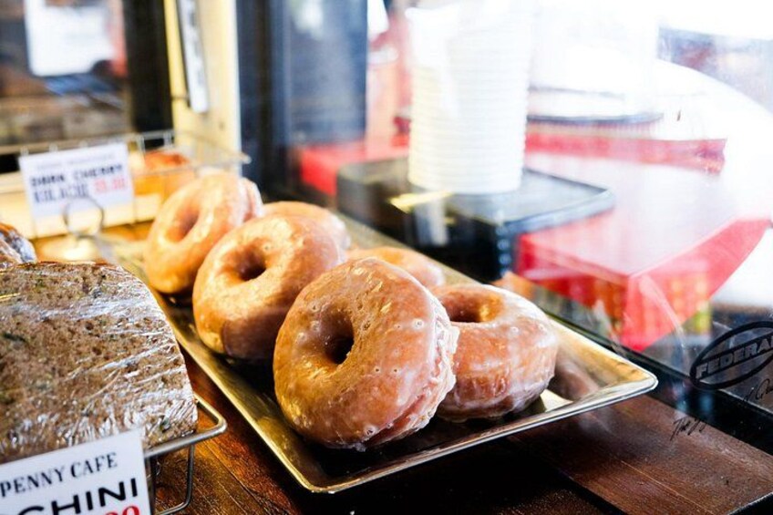 Glazed donuts on a tray, a sign for Penny Cafe, and a window with cups. 5