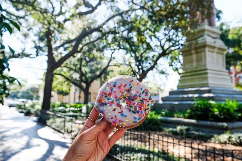 A hand holding a colorful donut with sprinkles. 2