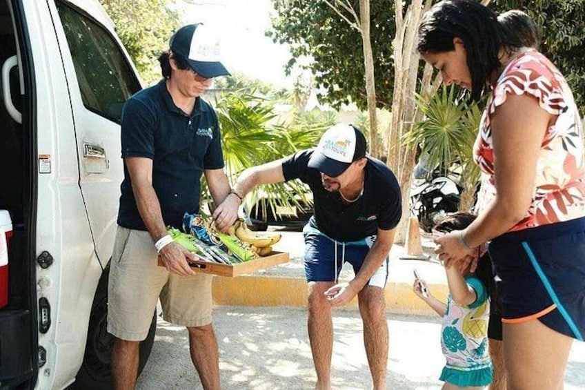 A group of people unloading a van, a child holding a toy, and a banana on the ground. 5