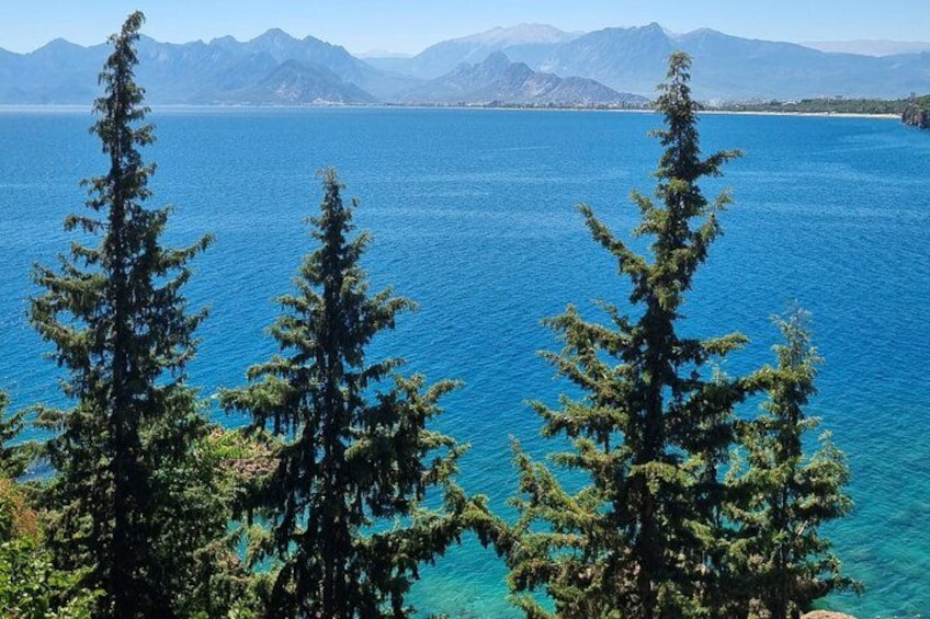 Un lago con aguas azul turquesa, rodeado de árboles de hoja perenne y montañas al fondo. 1