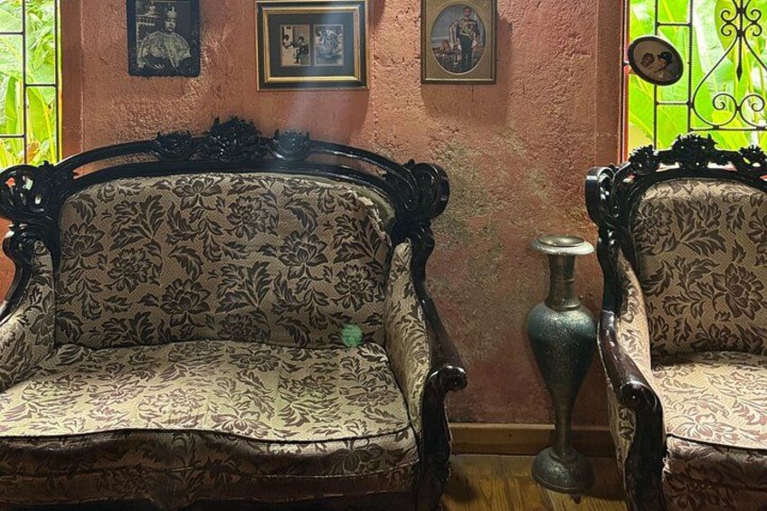 A vintage sofa with floral upholstery, a decorative vase, and framed pictures on the wall. 5