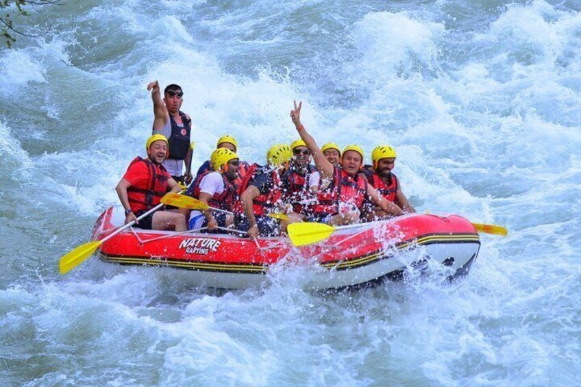 Un gruppo di persone su una zattera rossa con la scritta 'NATURE RAFTING', che affronta rapide impetuose. 4