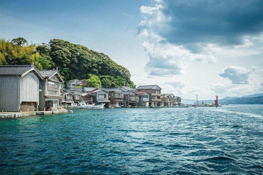 A coastal village with traditional wooden houses, a lighthouse, and a bridge over the water. 4