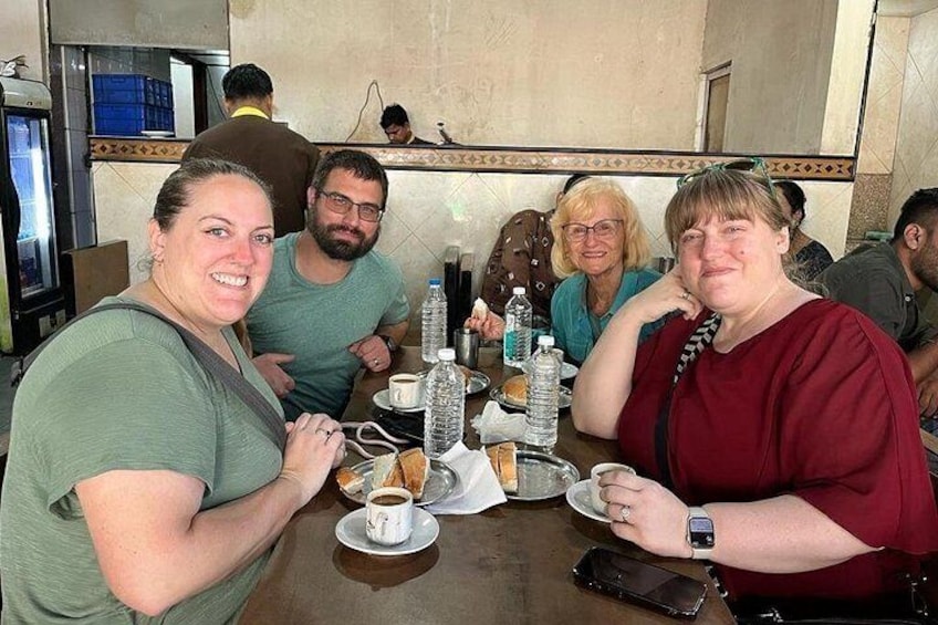 Un grupo de personas cenando en un restaurante con mesas dispuestas, platos, vasos y botellas. 3