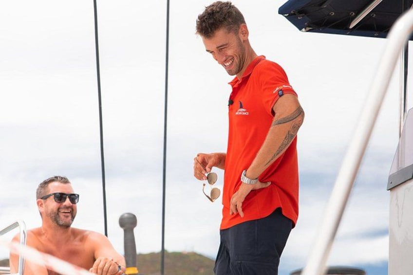 Une personne portant un t-shirt rouge, debout sur un bateau et tenant des lunettes de soleil. 5