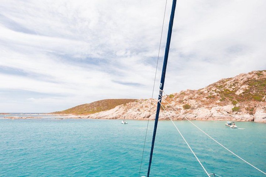 Un velero en aguas turquesas, con colinas rocosas al fondo. 4