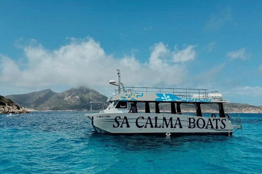 Ein Boot mit dem Namen 'SA CALMA BOATS' auf dem Wasser, mit einer gebirgigen Landschaft im Hintergrund. 4