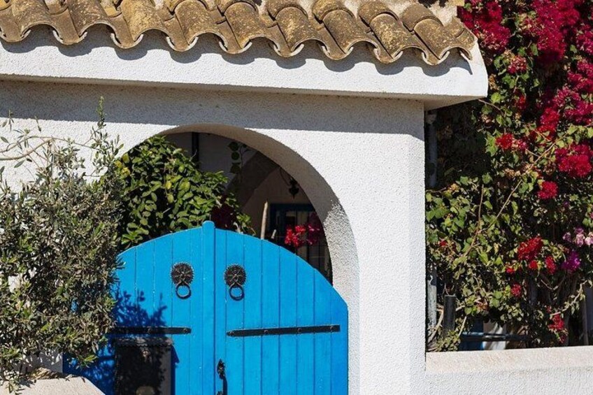 Una puerta azul con un muro blanco y techo de tejas. 2