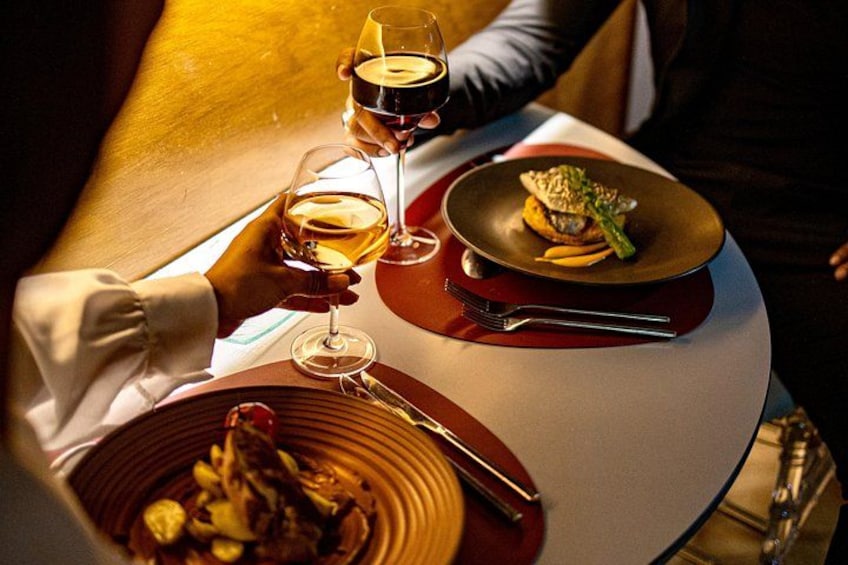 Una mesa de comedor con un plato de comida, una copa de vino y un tenedor. 3