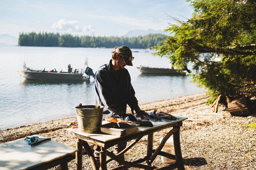 A person fishing by a lakeside with a boat in the background. 3