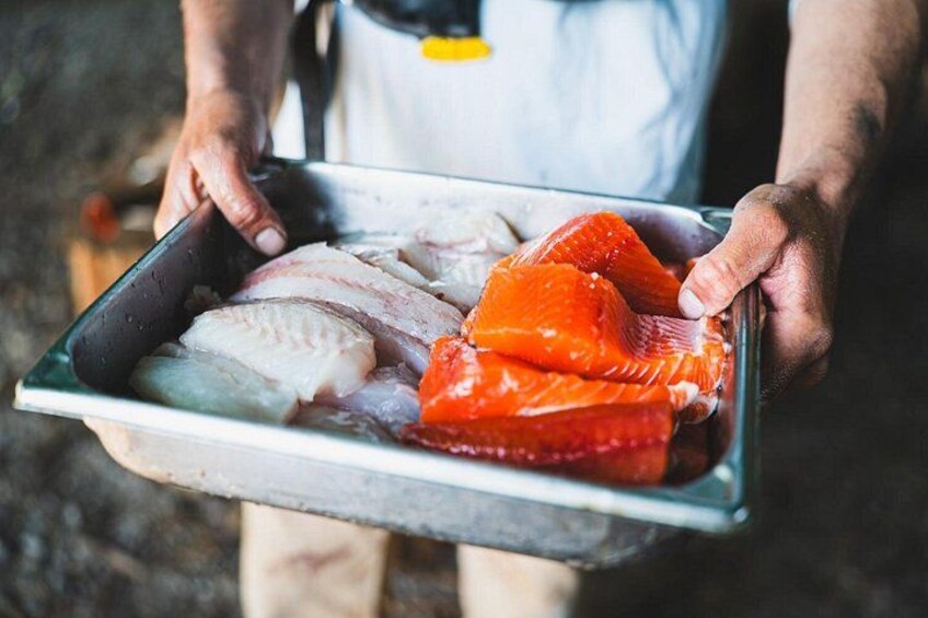 A person holding a tray with various types of fish. 4