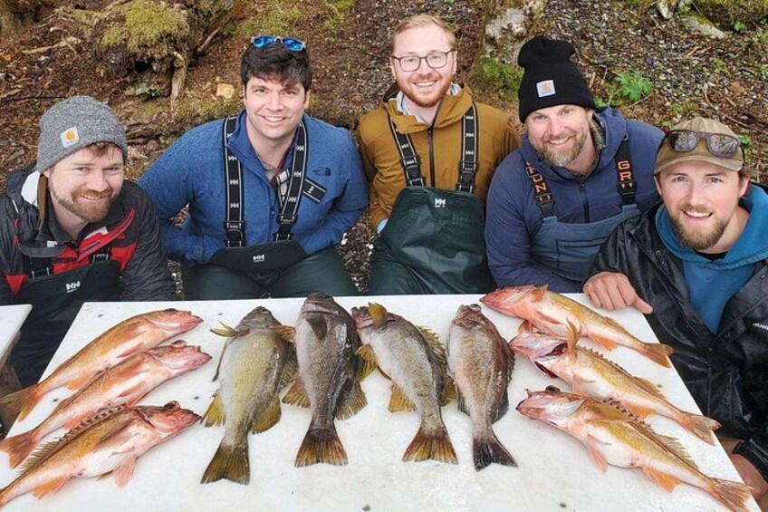 Five people sitting around a table with various fish. 1