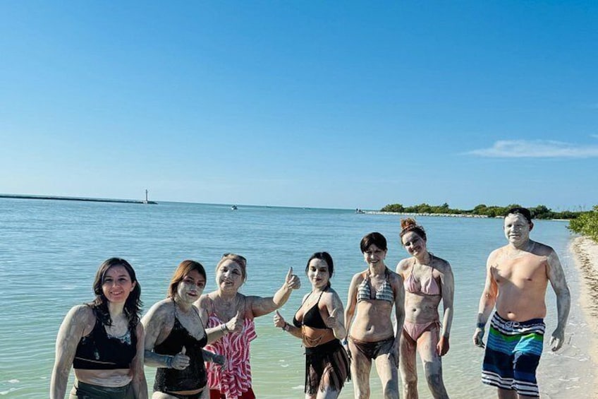 En gruppe mennesker står på en strand med hav i baggrunden. 2