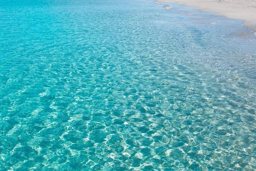 A clear turquoise sea with visible sandbars and a sandy beach. 3