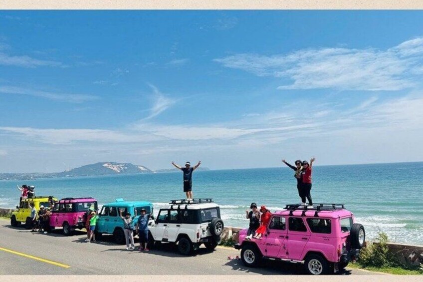 Eine Gruppe bunter Fahrzeuge steht am Strand, und Menschen stehen darauf. 5