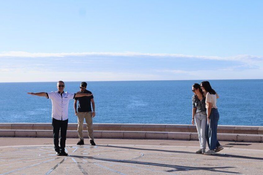A group of people standing on a promenade overlooking the sea. 4