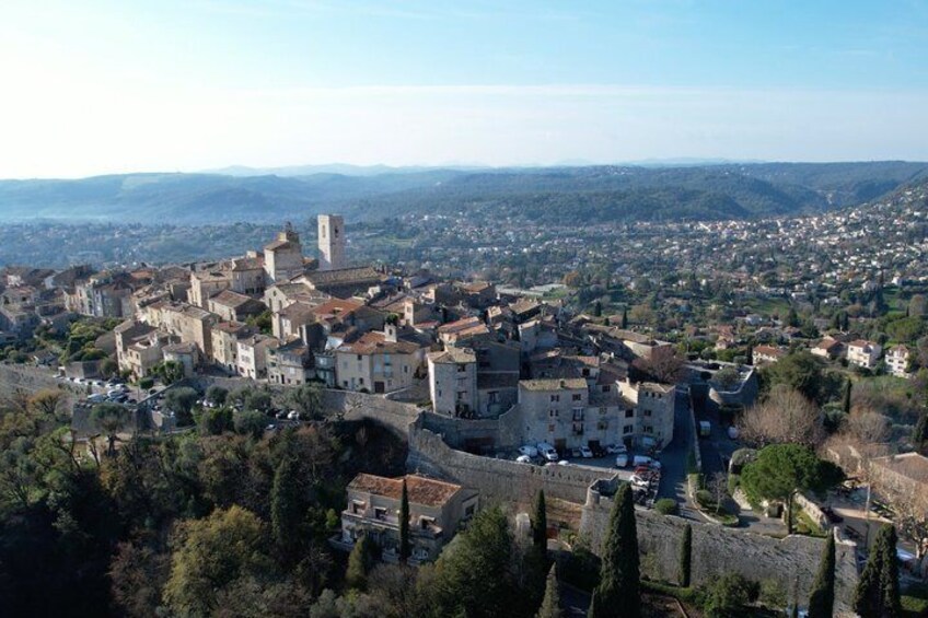 A historic town with a prominent castle, surrounded by dense greenery and a mountainous backdrop. 2