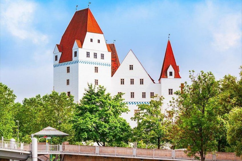 Un château aux toits rouges et aux murs blancs, entouré d’arbres et surplombé par un pont. 4