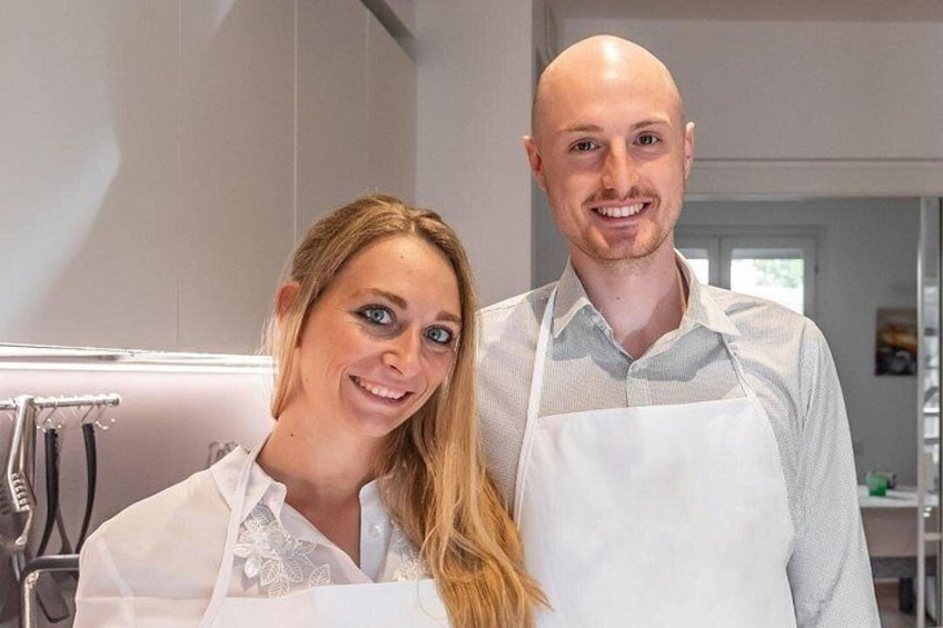 Dos personas en una cocina, una con delantal blanco y la otra con camisa blanca. 1