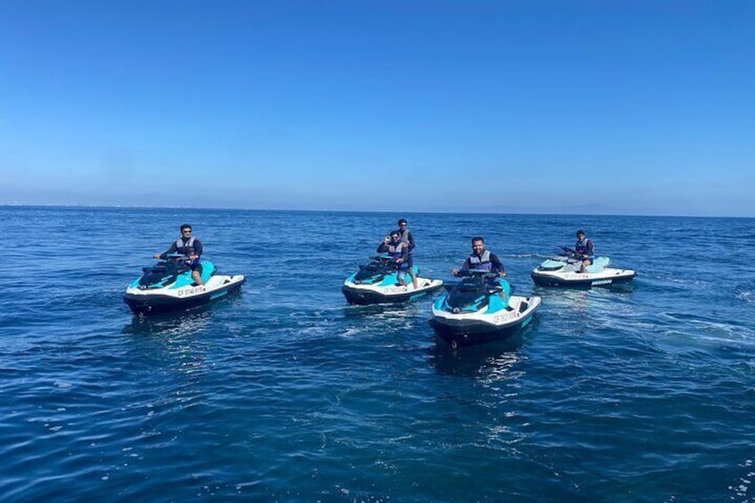 Quattro persone che sfrecciano sui jet ski su un mare calmo sotto un cielo sereno. 5