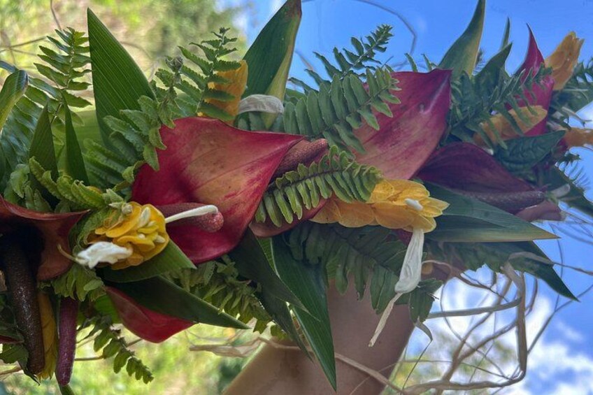 A bouquet of flowers with red and yellow blooms, green foliage, and fern-like leaves. 3