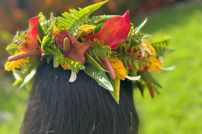 A person wearing a floral headpiece with green leaves, red flowers, and yellow blooms. 2