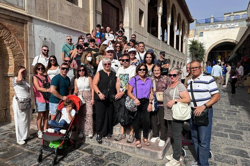 A group of people standing on a stone-paved street with historical buildings in the background. 5