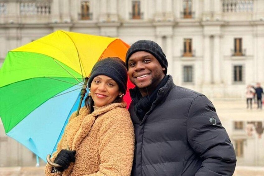 Un couple se tient devant un bâtiment historique, un parapluie coloré à la main. 5
